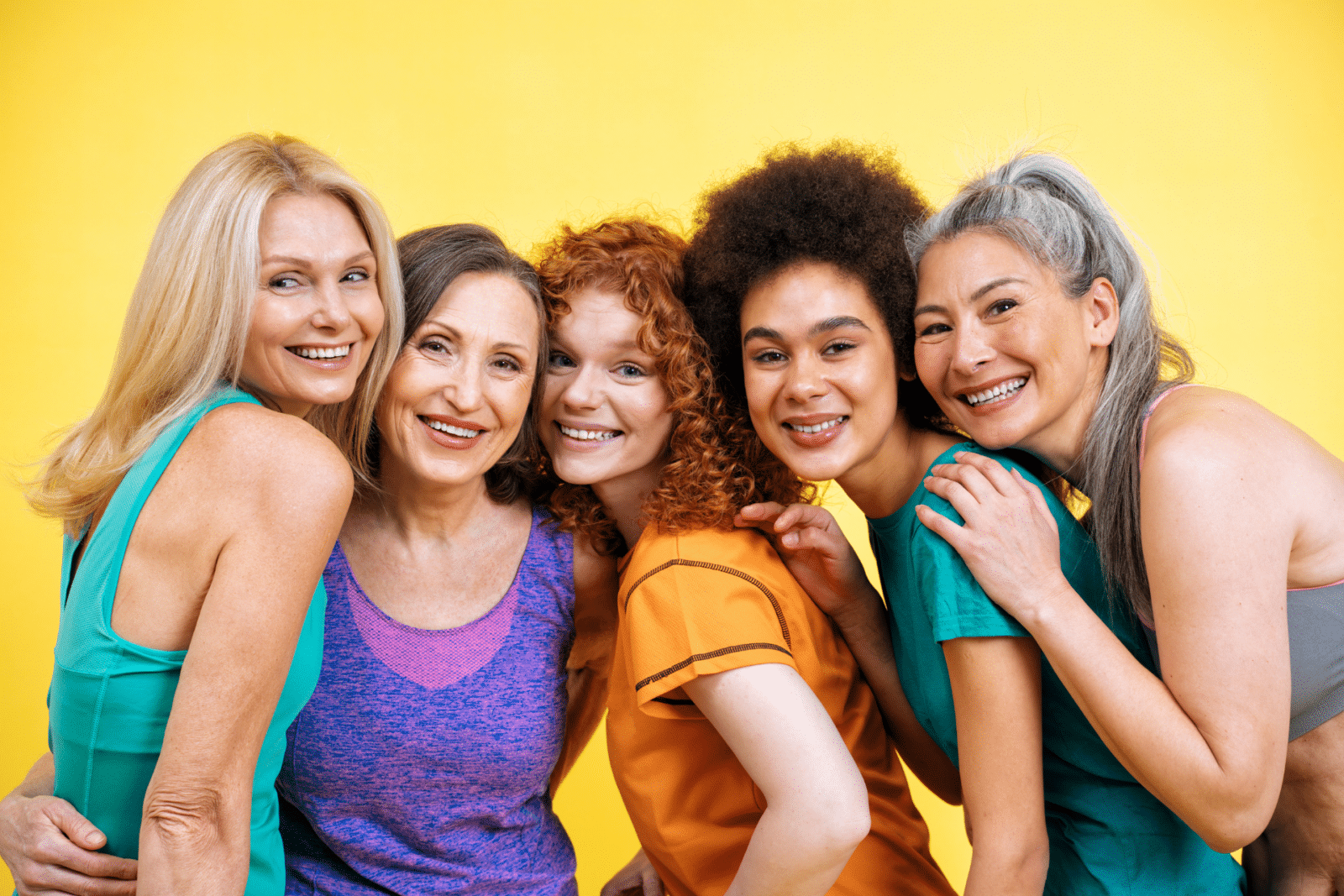 Five middle aged women lean in and smile.